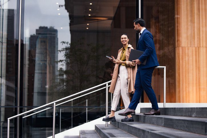 Two young professionals walking down steps talking about their careers