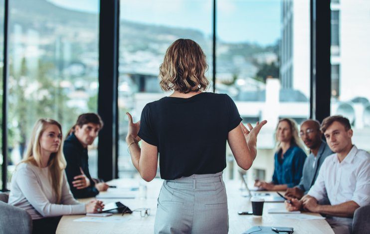A leader speaking to her team around a meeting table